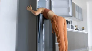 On a hot day, the girl cools with his head in the refrigerator